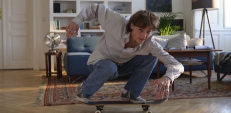Junger Mann fährt Skateboard im Wohnzimmer