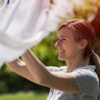 Frau hängt Wäsche im Garten auf